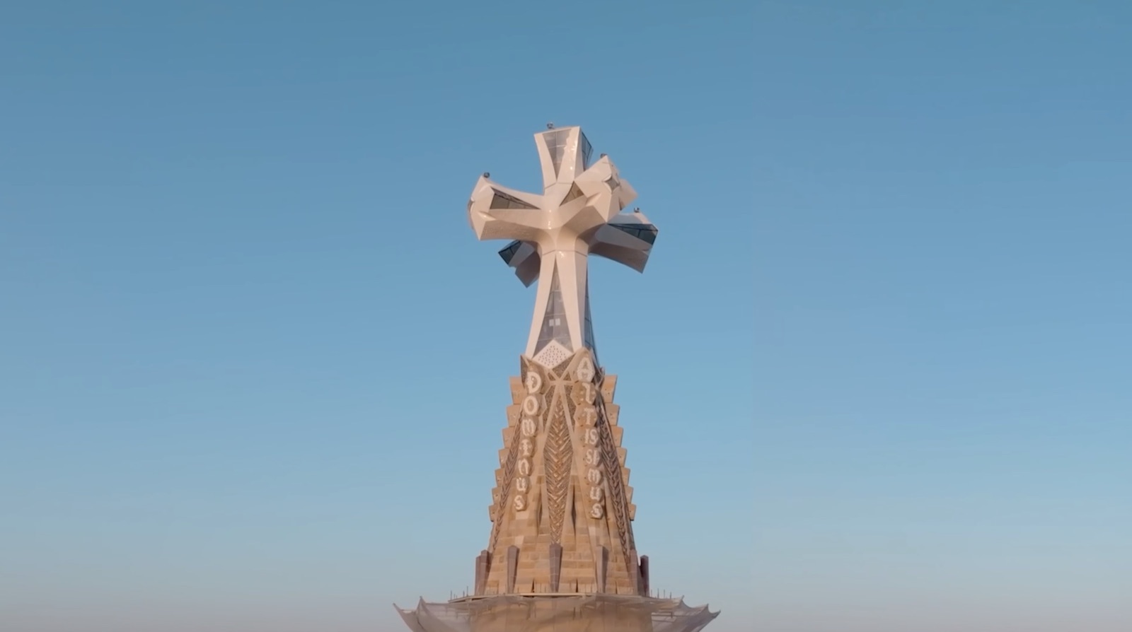 La cruz de la torre de Jesucristo de la Sagrada Família sobre el cielo azul.