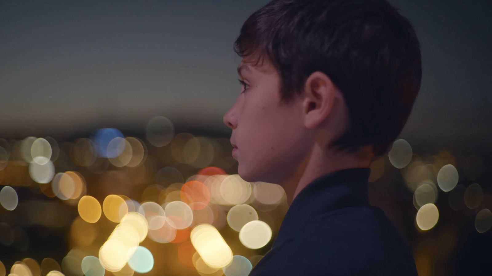 Un niño mira Barcelona al atardecer.